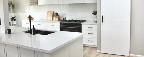 Custom kitchen featuring Janper vinyl shaker-style doors and natural quartz bench tops.